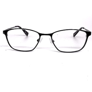 May include: Black eyeglasses with a thin, oval frame. The lenses are clear, and the nose pads are transparent. The temples are also black and have a subtle design. The glasses are set against a white background.