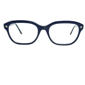 May include: Dark navy blue eyeglasses with a rounded cat-eye shape. The frames have a glossy finish and small gold-colored accents on the outer corners. The lenses are clear, and the temples are thin and dark.