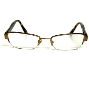 May include: Semi-rimless eyeglasses featuring a metallic bronze frame with rectangular lenses. The temples display a brown and black tortoiseshell pattern, complemented by adjustable gold-toned nose pads for a secure fit and clear vision.