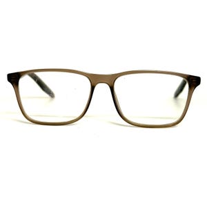 May include: Full-rim spectacles featuring a translucent, smoky brown plastic frame with a rectangular shape. The clear lenses are set within the smooth, rounded edges of the frame, which includes integrated nose pads and straight, dark-tipped temples.