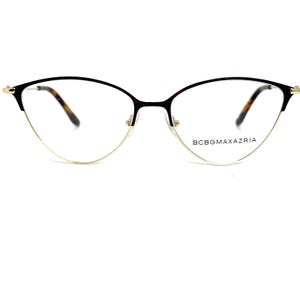 May include: Cat-eye eyeglasses with a gold-tone metal frame and black upper rims. The lenses are clear, and the temples feature a tortoiseshell pattern. The brand name, BCBGMAXAZRIA, is printed on the right lens.