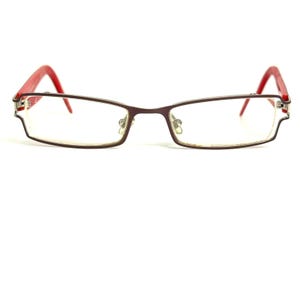 Peut inclure: Lunettes rectangulaires dotées d'une monture en métal brun foncé aux lignes fines et droites. Les branches sont d'une couleur rouge vif contrastante, s'étendant vers l'extérieur depuis les charnières. Les verres clairs sont maintenus par une structure.