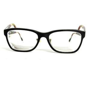 May include: Black rectangular eyeglasses with clear lenses. The frames feature a glossy black front with thin, multicolored patterned temples that transition into a subtle mix of muted tones at the tips, providing a distinct contrast to the solid front.