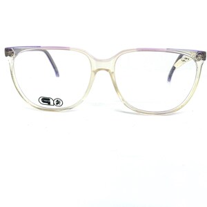 May include: Clear plastic spectacles with a purple frame and a black logo that says "G" with a small symbol next to it.