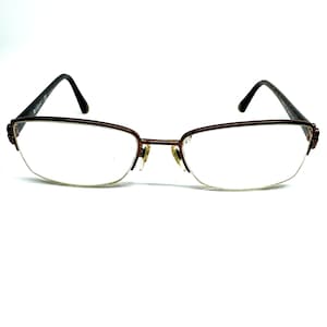 Puede incluir: Un par de gafas de metal marrón con un diseño sin montura y lentes transparentes.