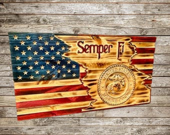 May include: A wooden American flag with a distressed look, featuring the words "Semper Fi" and the United States Marine Corps emblem. The flag is painted in red, white, and blue.