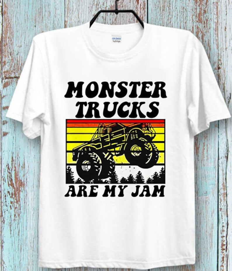 May include: White t-shirt with a black and white graphic of a monster truck with the text "Monster Trucks Are My Jam" in black and yellow.