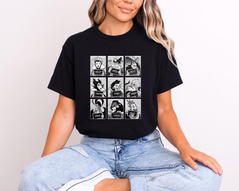 Puede incluir: Camiseta negra con una cuadr&iacute;cula de nueve ilustraciones en blanco y negro de villanos animados, cada una con un a&ntilde;o de lanzamiento. La camiseta es de cuello redondo y la lleva una persona.