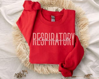 Op de afbeelding: Een felrood sweatshirt met ronde hals voorzien van het woord RESPIRATORY in grote, dikgedrukte, lichtgekleurde hoofdletters, met het woord therapist in een wit, cursief lettertype direct over het midden van de tekst.