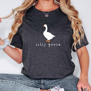 K&ouml;nnte beinhalten: Ein dunkel-melierter grauer T-Shirt mit einer wei&szlig;en G&auml;nse-Illustration und dem Text "silly goose."
