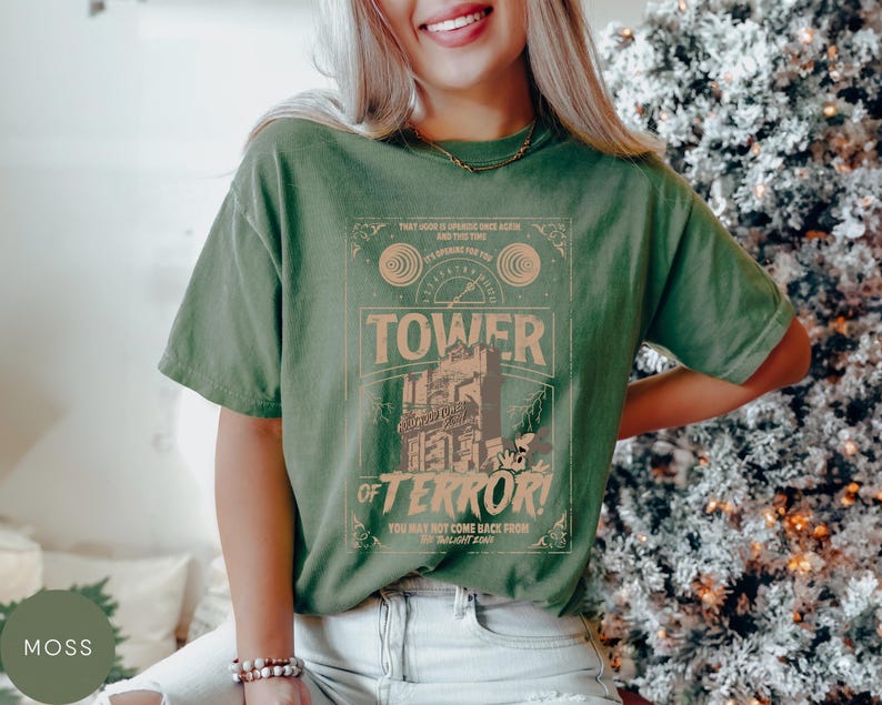 May include: Moss green t-shirt with a graphic featuring the words "Tower of Terror" and the text "That God is speaking once again and the time is speaking for you". The shirt has a vintage, distressed look.