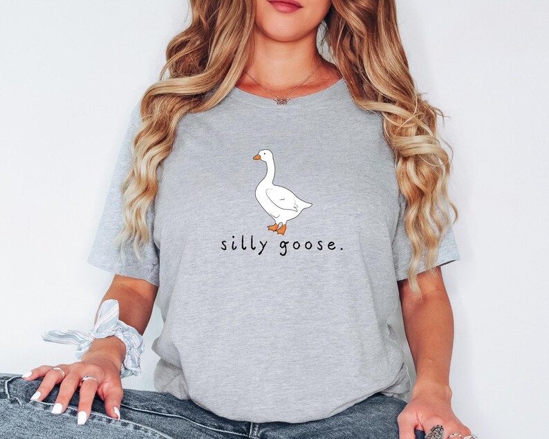 K&ouml;nnte beinhalten: Ein graues T-Shirt mit einer wei&szlig;en G&auml;nse-Illustration und dem Text "silly goose."