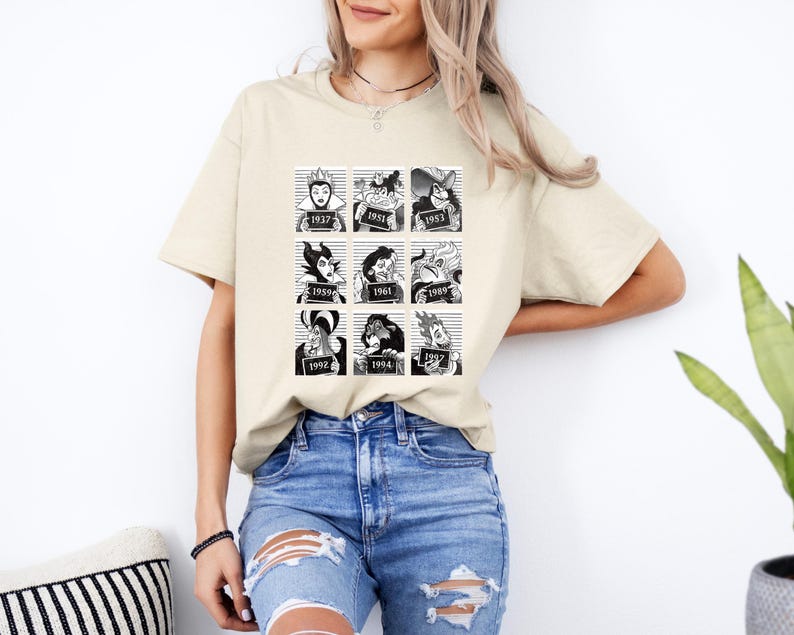Puede incluir: Camiseta beige con un gr&aacute;fico en blanco y negro de villanos de Disney en cajas estilo ficha policial, cada una con un a&ntilde;o. La camiseta la lleva una persona con cabello claro y vaqueros azules.