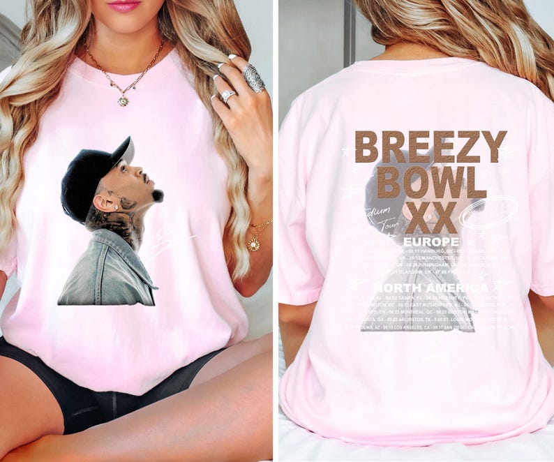 May include: A light pink t-shirt featuring a graphic of a man looking upwards, wearing a black cap and denim jacket. The back of the shirt displays the text "BREEZY BOWL XX EUROPE" and a list of tour dates.