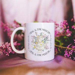 May include: White ceramic mug with a floral design and the text "OPAL & JUNE MOCKUPS" on both sides. The mug is sitting on a purple fabric surface with purple flowers.