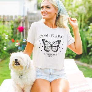 May include: A white t-shirt with a black butterfly graphic and the text "OPAL & JUNE" and "YOUR DESIGN HERE".