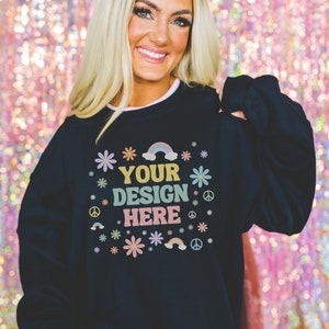May include: Black sweatshirt with a colorful graphic design that says "YOUR DESIGN HERE" surrounded by flowers, rainbows, and peace signs.