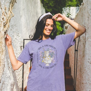 May include: A purple t-shirt with a circular graphic featuring a bust, flowers, and the text "OPAL & JUNE MOCKUPS". The shirt is worn with denim shorts and a white headband. The text "your designs will love this" is also visible.