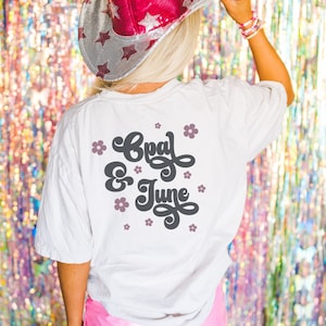May include: White t-shirt with the text "Opal & June" in a retro font with pink flowers around the text.