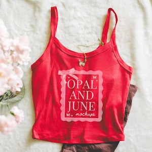 Op de afbeelding: Een rode camisole met dunne bandjes, met de tekst "OPAL AND JUNE mockups" in een roze kader. Een gouden vlinderhangerketting rust op de camisole. Bruin gestreepte broek is gedeeltelijk zichtbaar.