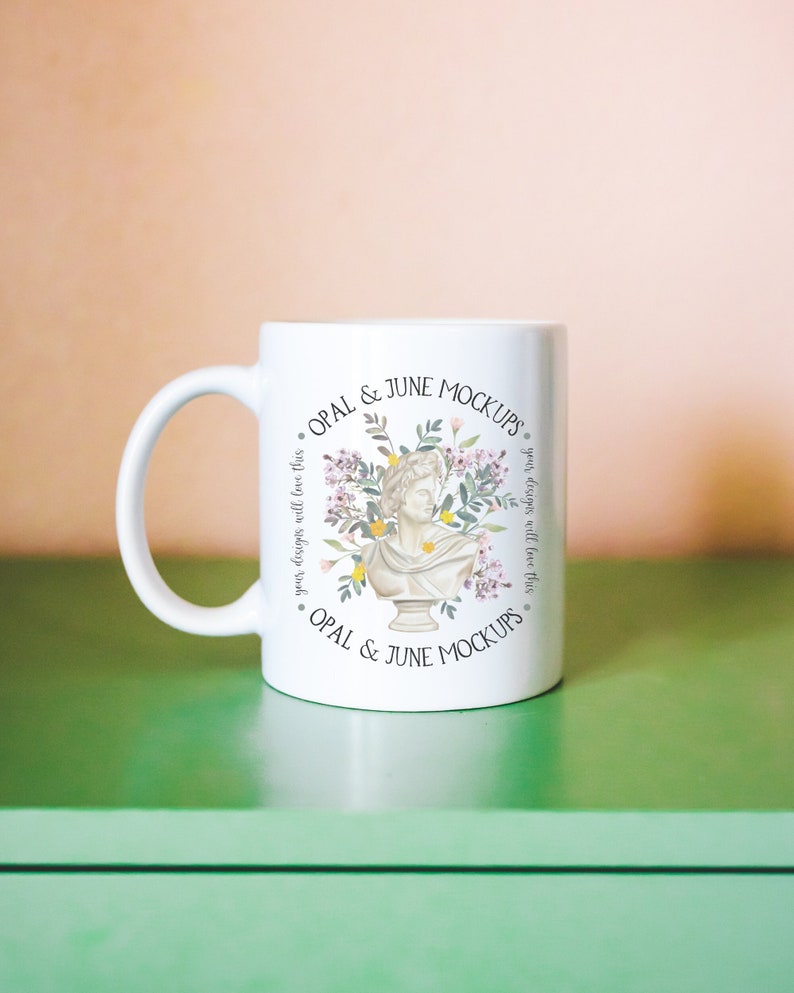 Puede incluir: Taza de cer&aacute;mica blanca con un dise&ntilde;o floral que presenta un busto de mujer. La taza tiene el texto "OPAL & JUNE MOCKUPS" impreso en la parte delantera.
