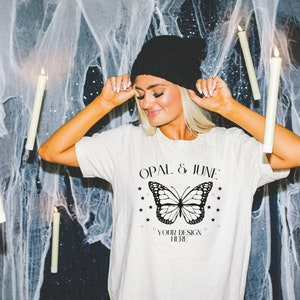 May include: A white t-shirt with a black butterfly graphic and the text "Opal & June" and "Your Design Here".