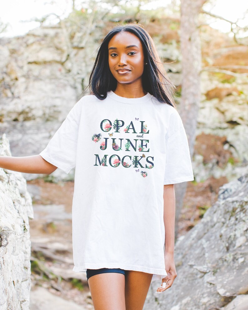 K&ouml;nnte beinhalten: Wei&szlig;es Oversize-T-Shirt mit floralem Design und dem Aufdruck "OPAL and JUNE MOCKS" auf der Vorderseite.