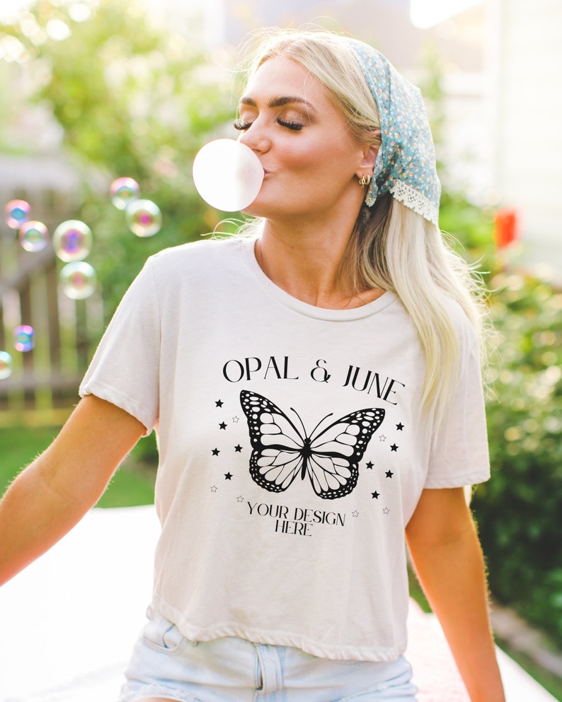 Puede incluir: Camiseta blanca recortada con un gr&aacute;fico de mariposa negra y el texto "Opal & June" y "Your Design Here".