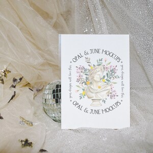 May include: A white card with a floral design and the text "OPAL & JUNE MOCKUPS" on a white background. The card is sitting on a sparkly, light brown fabric.