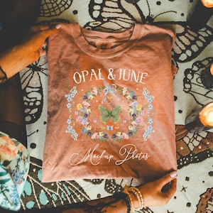 May include: A peach-colored t-shirt with a floral design and the text "Opal & June Mockup Photos".