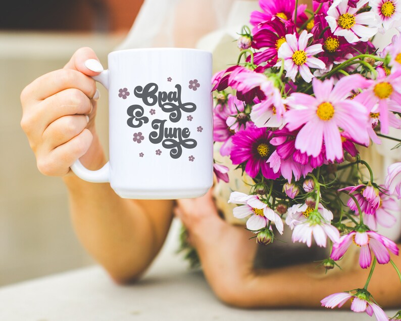 Puede incluir: Taza de cer&aacute;mica blanca con un dise&ntilde;o en blanco y negro que dice "Opal & June" con flores rosas alrededor del texto.