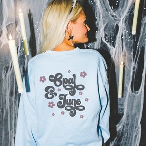 Back of Light Blue Sweatshirt Mockup for Halloween with Spooky Witchy Vibe: Colorful Photo of Model Wearing Light Blue Gildan 18000 Crewneck