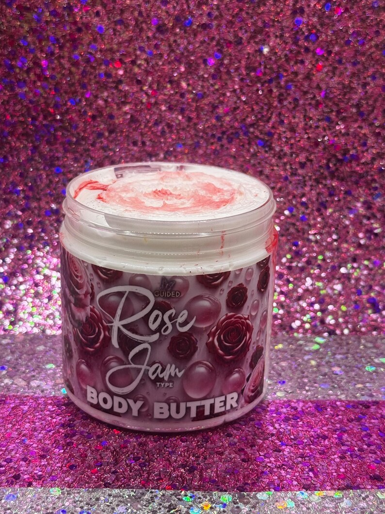 May include: A white jar with a pink lid and a pink and white label. The label says "Rose Jam Type Body Butter" and has a pink rose design.