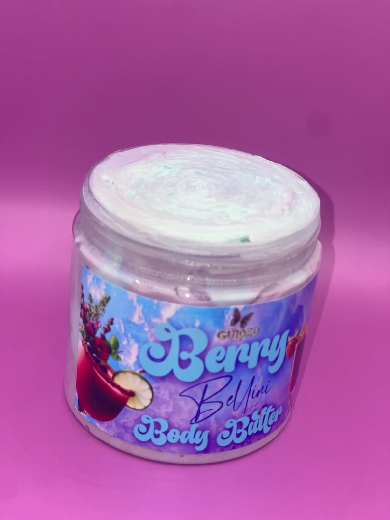 May include: A white jar of Gummy Berry Bellini Body Butter with a blue and white swirl on top. The jar has a colorful label with a butterfly logo, a glass of berry drink, and the text "Gummy Berry Bellini Body Butter".