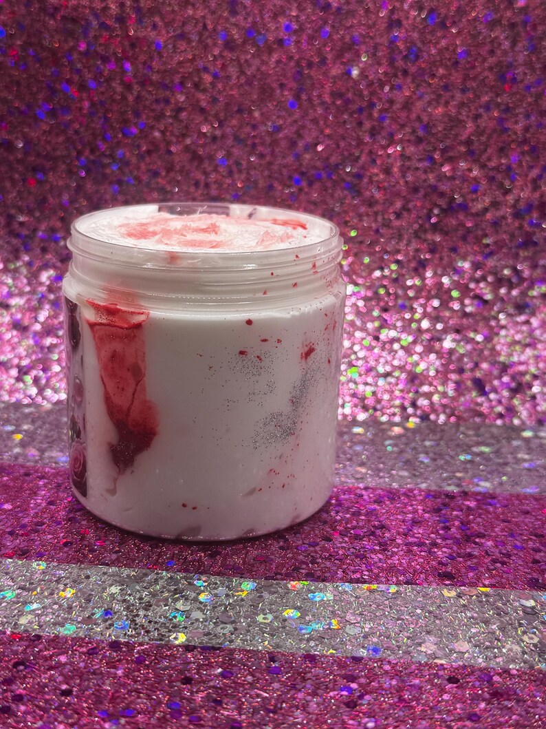 May include: A white jar with a red and white swirl design. The jar is filled with a white substance and has a red lid.