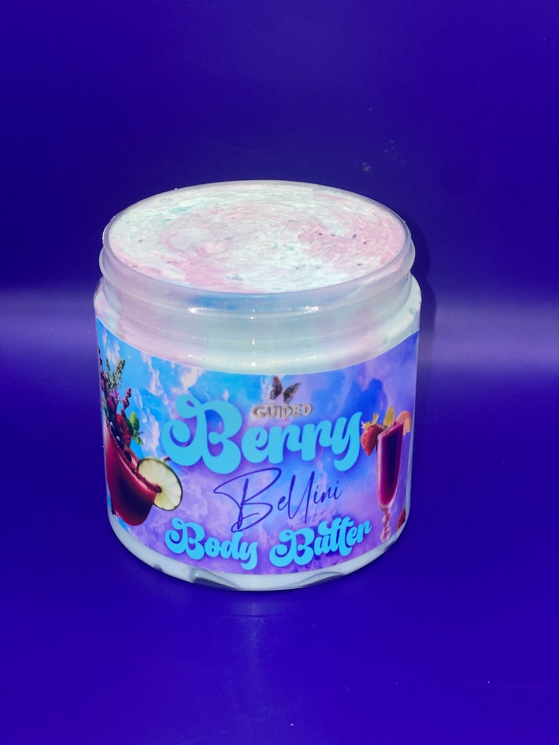 May include: A white jar of body butter with a pink and blue swirl on top. The label says "Guided Berry Bellini Body Butter".