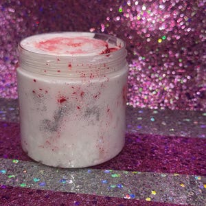 May include: A white jar with a pink and silver glitter swirl inside. The jar is sitting on a pink and silver glitter background.