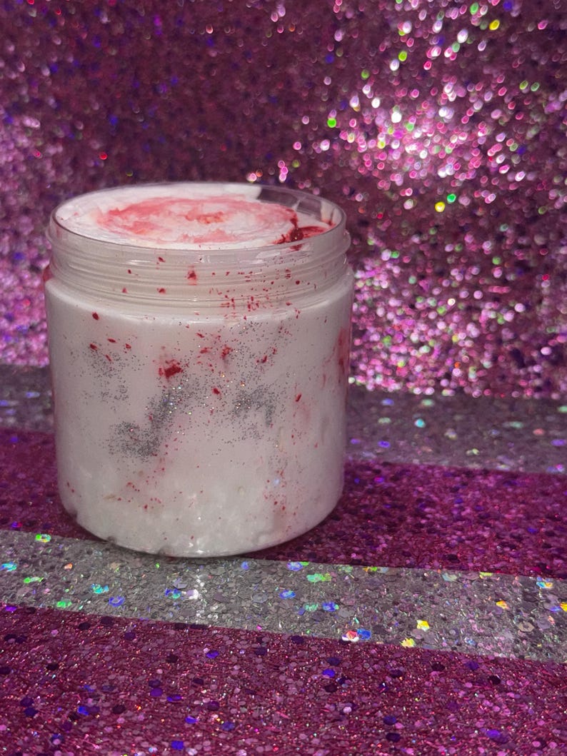 May include: A white jar with a pink and silver glitter swirl inside. The jar is sitting on a pink and silver glitter background.