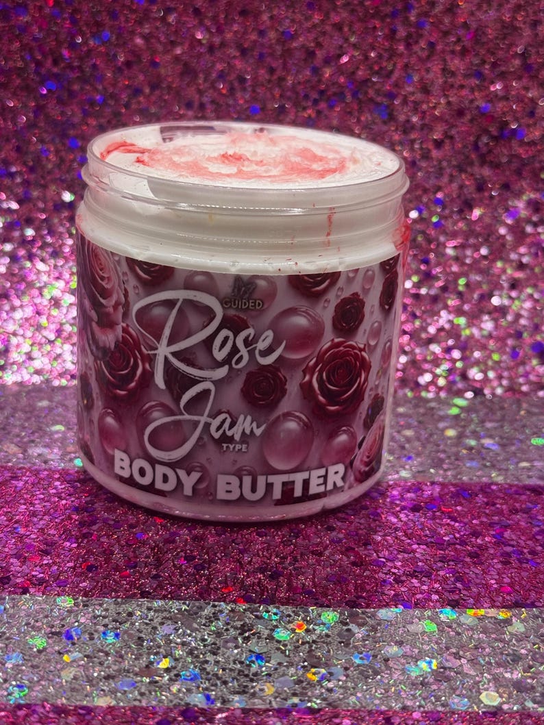 May include: A white jar with a pink lid and a pink and white label. The label says "Guided Rose Jam Type Body Butter".
