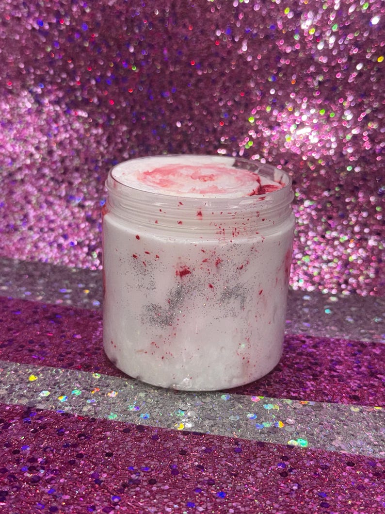 May include: A white jar with a pink and silver glitter swirl inside. The jar is sitting on a pink and silver glitter background.