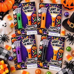 May include: Four rectangular Halloween-themed cards featuring a small plastic flashlight attached to each. The cards display the text LIGHT UP THE NIGHT! and HAPPY HALLOWEEN, with illustrations of pumpkins, ghosts, and candy. Each card includes a from: Jacob label.