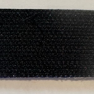 May include: A black hook and loop fastener, also known as Velcro, with a textured surface.