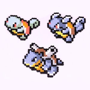 May include: Three pixel art Pokemon characters made with perler beads. The characters are Squirtle, Blastoise, and Wartortle. Squirtle is blue and orange, Blastoise is blue and yellow, and Wartortle is blue, orange, and yellow.