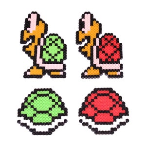 May include: Two pixel art turtle shell characters, one green and one red, with their corresponding shells below. The characters are in a standing position with their heads and legs visible.