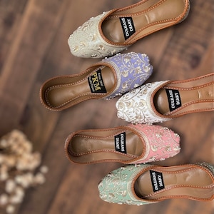 K&ouml;nnte beinhalten: F&uuml;nf Paar bestickte Damenschuhe in verschiedenen Farben. Die Schuhe sind alle flach und haben eine spitze Zehenpartie. Die Stickerei ist aufwendig und zeigt Blumenmuster. Die Schuhe sind alle aus einem weichen, bequemen Material gefertigt. Die Schuhe sind auf der Sohle mit "Dulhans Diary" gekennzeichnet.
