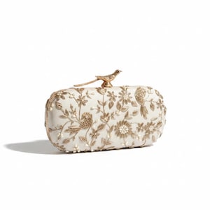 Può includere: Una pochette rettangolare color bianco sporco con intricati ricami in filo metallico dorato raffiguranti motivi floreali e uccelli. La borsa è dotata di una chiusura in metallo dorato a forma di uccello e piccoli dettagli in perline.