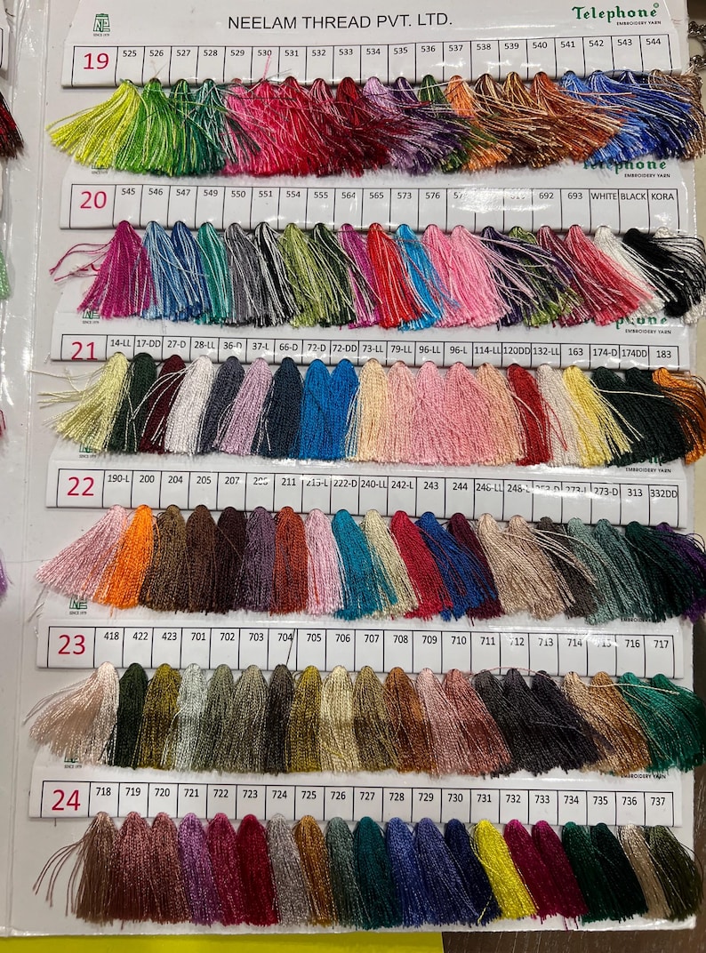 May include: A color chart of embroidery thread tassels in various colors, including green, red, pink, and blue. The chart is labeled with numbers and codes, and the brand name "NEELAM THREAD PVT. LTD." is visible.