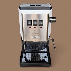 May include: A white and stainless steel espresso machine with a black drip tray. The machine has three buttons with icons for single, double, and hot water. The machine has the text "Barista Gadgets" and "Gaggia" on the front.