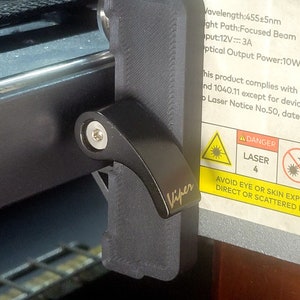 May include: A black plastic laser safety switch with the word "Viper" printed on it. The switch is attached to a laser engraver with a warning label that reads "DANGER LASER 4 AVOID EYE OR SKIN EXPOSURE TO DIRECT OR SCATTERED RADIATION".