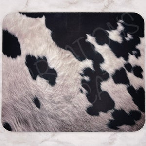 May include: Black and white cowhide pattern bath mat. The mat has a soft, fuzzy texture and is perfect for adding a touch of rustic charm to your bathroom.